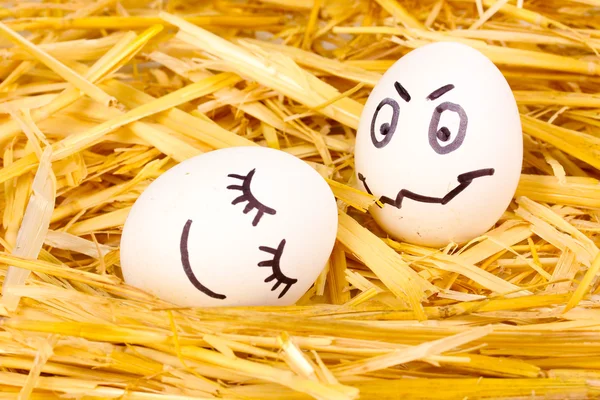 Witte eieren met grappige gezichten in stro — Stockfoto