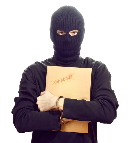 Bandido em máscara preta em algemas com envelope ultra secreto isolado em branco — Fotografia de Stock