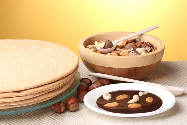 Kuchen für Kuchen auf Glasständer und Nüsse auf Tisch auf gelbem Hintergrund — Stockfoto