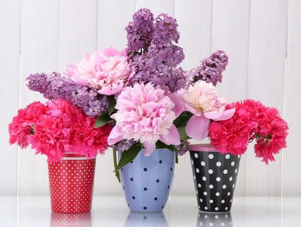 Jarní květiny v pohárech na stolku na bílém pozadí dřevěná — Stock fotografie
