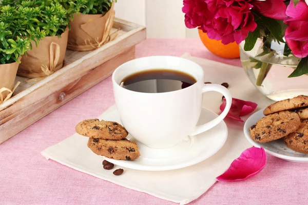 Чашка кофе, печенье, апельсин и цветы на столе в кафе — стоковое фото