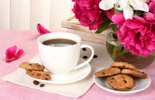 Filiżankę kawy, ciasteczka i kwiaty na stole w kawiarni — Zdjęcie stockowe