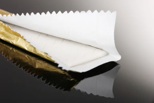 Chewing gum on the wrapping foil on gray background — Stock Photo, Image