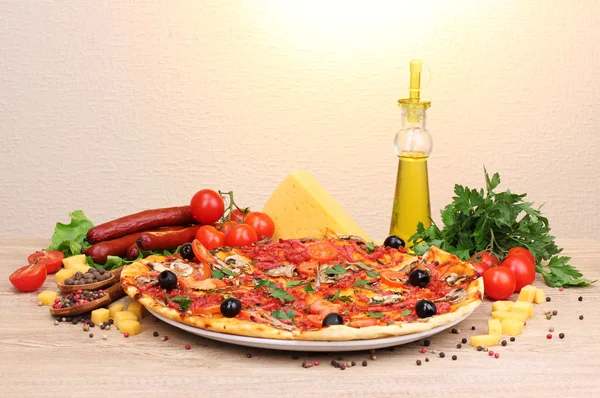 Delicious pizza, vegetables and salami on wooden table — Stock Photo, Image