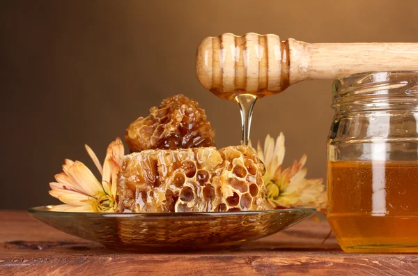 Jarra de mel, favos de mel e drizzler de madeira na mesa sobre fundo amarelo — Fotografia de Stock