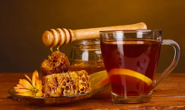 Μέλι, λεμόνι, κηρήθρα και ένα φλιτζάνι του τσαγιού στο ξύλινο τραπέζι για καφέ φόντο — Φωτογραφία Αρχείου