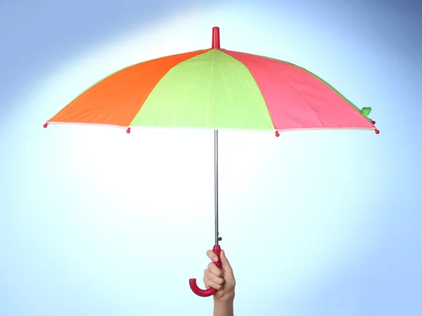 Flerfärgad paraply i handen på blå bakgrund — Stockfoto