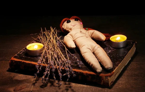 Кукла вуду на деревянном столе при свечах — стоковое фото