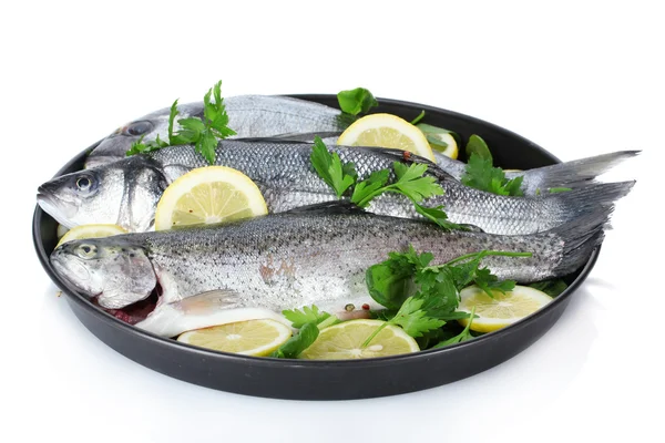 Pesci freschi con limone e prezzemolo su piatto isolato su bianco — Foto Stock