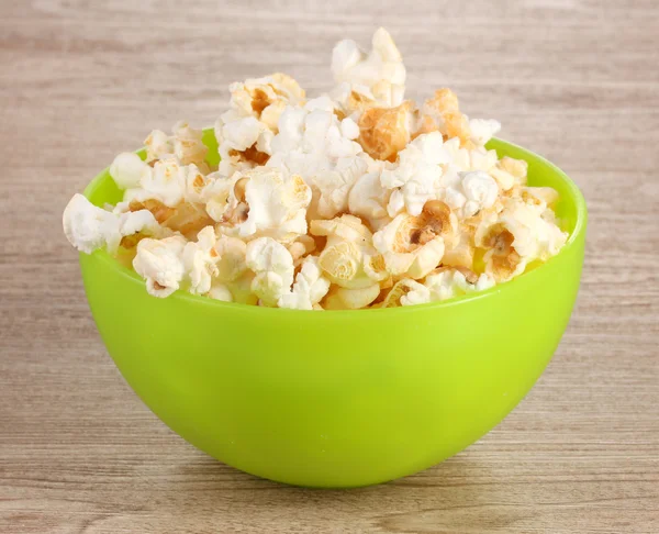 Popcorn in heller Plastikschüssel auf Holztisch — Stockfoto