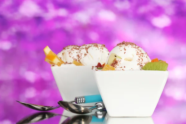 Вкусное ванильное мороженое с шоколадом и фруктами в мисках и ложках на фиолетовом фоне — стоковое фото
