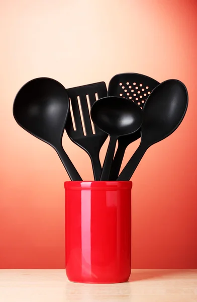 stock image Black kitchen utensils in cup on red bakground