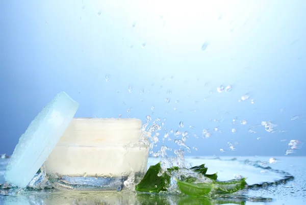 Geöffnetes Glas Sahne in Wasserspritzer auf blauem Hintergrund — Stockfoto