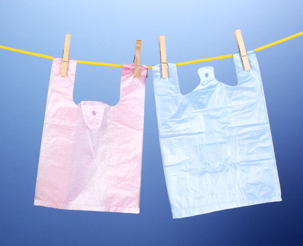 Целофановые мешки висят на веревке на синем фоне
