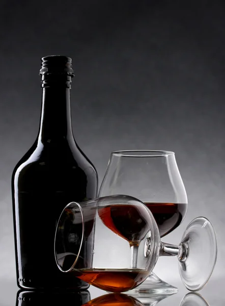 Gläser Schnaps und Flasche auf grauem Hintergrund — Stockfoto