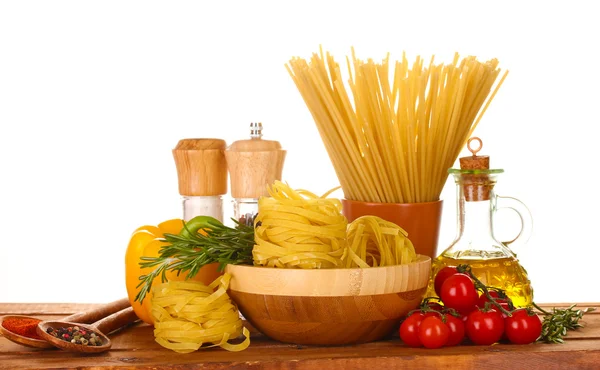 Спагетти, лапша в миске, банка масла и овощей на деревянном столе изолированы на белом — стоковое фото