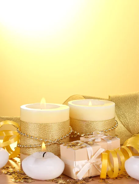 아름 다운 촛불, 선물 및 노란색 배경에 나무 테이블에 장식 — 스톡 사진