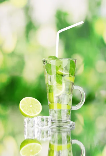 Verre de cocktail avec citron vert et menthe sur fond vert — Photo