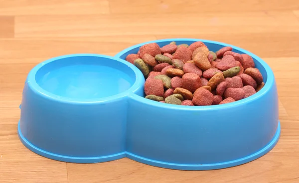 Dry dog food and water in blue bowl on the floor — Stock Photo, Image