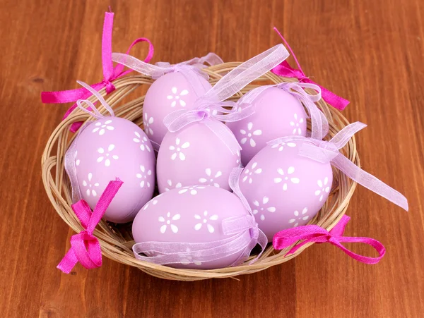 Huevos de Pascua coloridos en cesta sobre fondo de madera — Foto de Stock