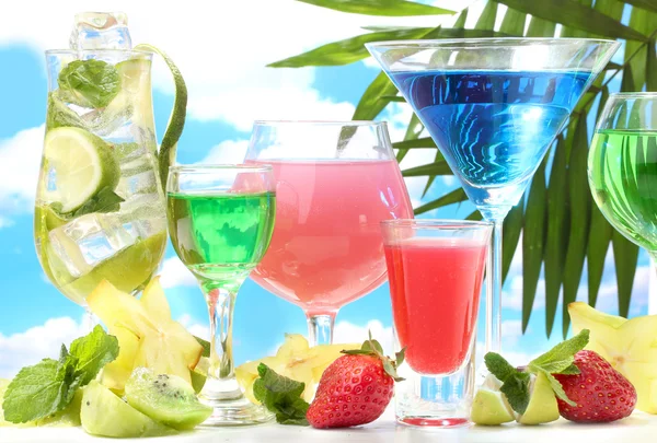 Glazen cocktails op tabel op blauwe hemelachtergrond — Stockfoto