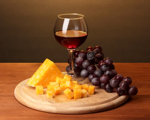 Vinho em vinho e queijo sobre mesa de madeira sobre fundo marrom — Fotografia de Stock