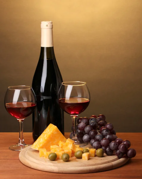 Bottiglia di grande vino con bicchieri da vino e formaggio su tavola di legno su sfondo marrone — Foto Stock