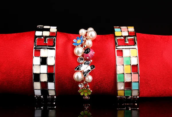 Três belas pulseiras no pano vermelho no fundo preto — Fotografia de Stock