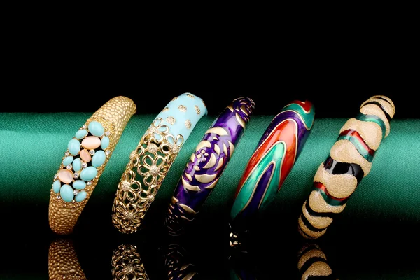 Five beautiful bracelets on the green cloth on black background — Stock Photo, Image