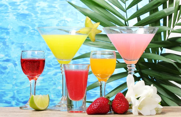 Cocktails exotiques et fleurs sur table sur fond bleu mer — Photo