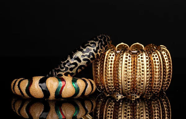 Schöne goldene Armbänder isoliert auf schwarzem Hintergrund — Stockfoto