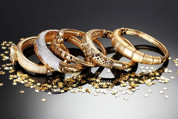 Piękne złote bransoletki na szarym tle — Zdjęcie stockowe