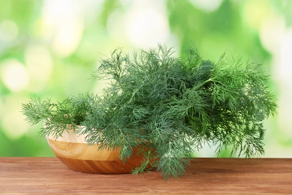 stock image Dill in a wooden bowl on green background