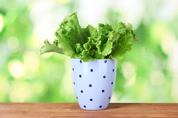 Salad in a lilac cup with black polka dots on green background — Stock Photo, Image