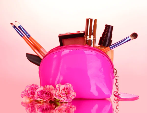 Maquiagem saco com cosméticos e escovas em fundo rosa — Fotografia de Stock