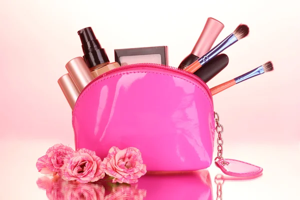 Bolsa de maquillaje con cosméticos y pinceles sobre fondo rosa — Foto de Stock