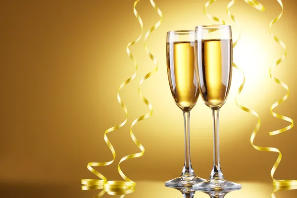Bicchieri di champagne e streamer su sfondo giallo — Foto Stock