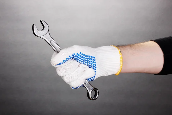 Курок в руці з захисною рукавичкою на сірому фоні — стокове фото