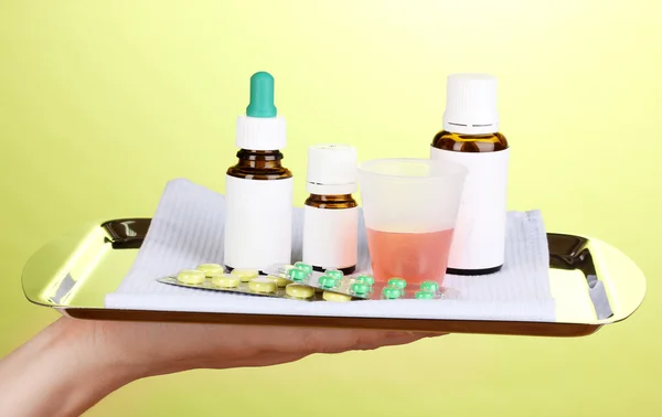 Hand holding tray with medicines on green background — Stock Photo, Image