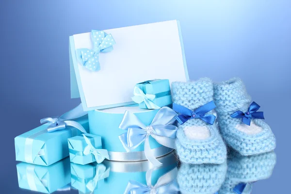 Schöne Geschenke, Babystiefel, leere Postkarte und Schnuller auf blauem Hintergrund — Stockfoto