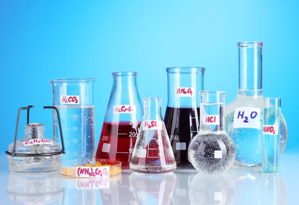 Tubes à essai avec divers acides et produits chimiques sur fond bleu — Photo