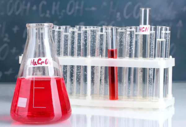 Тестові труби з різними кислотами та іншими хімічними речовинами на тлі дошки — стокове фото