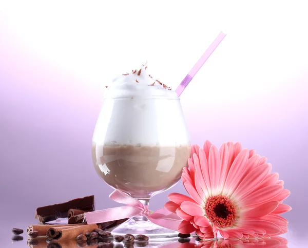 Glass of coffee cocktail and gerbera flower on purple background