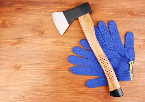 Axe and gloves on wooden background — Stock Photo, Image