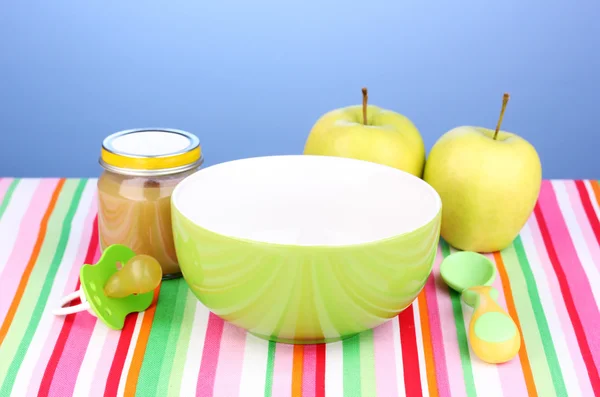 stock image Jar of baby puree with plate and spoon on napkin on blue background