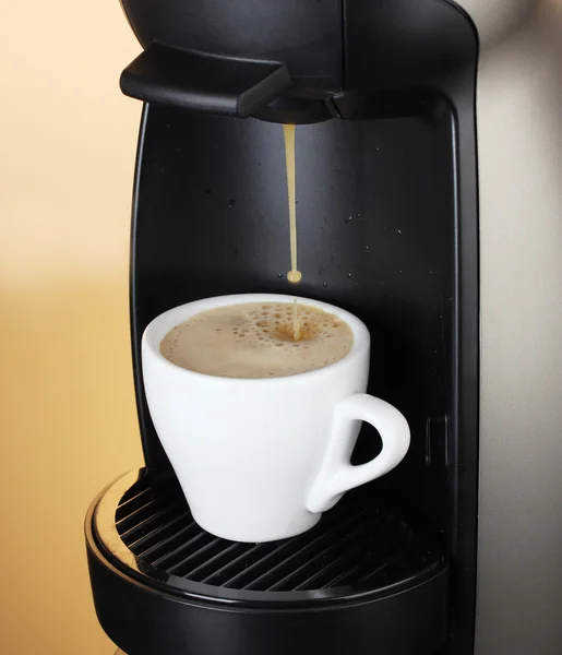 갈색 배경에 커피를 컵에 붓는 에스프레소 기계 — 스톡 사진
