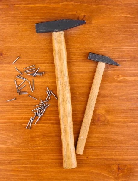 Martillos y clavos de metal sobre fondo de madera — Foto de Stock