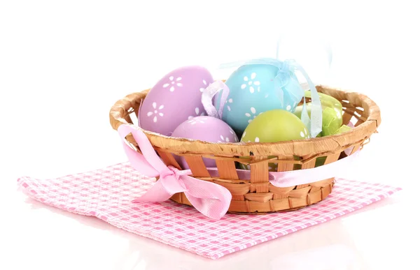 Uova di Pasqua variopinte in cesto su tovagliolo isolato su bianco — Foto Stock