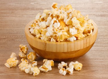 Popcorn in wooden bowl on wooden table clipart