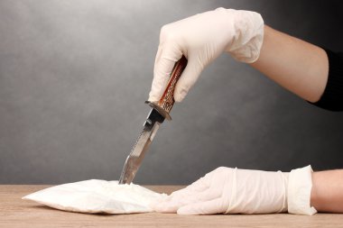 Packets of Cocaine opening with a knife on wooden table on grey background clipart